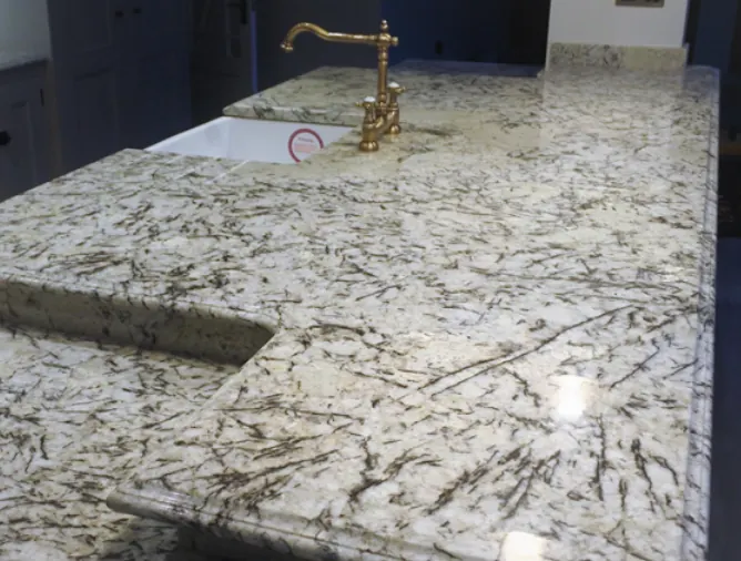 White Sensa granite kitchen worktop with dark veining and a brass tap